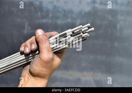 Welding electrodes in the hands of the worker. Steel welding rod. Welding electrode.Iron and steel welding stick. Stock Photo
