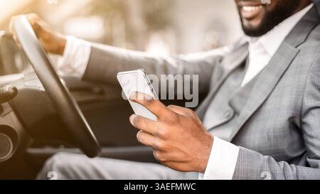 Black guy in suit using smartphone while driving Stock Photo
