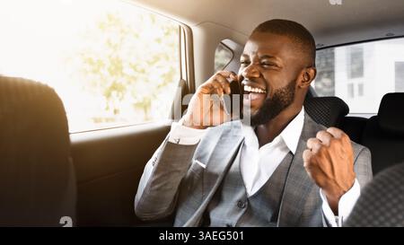 Delighted african entrepreneur having pleasant conversation on phone in car Stock Photo