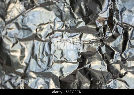 Silvery metallic crumpled foil texture. Selective focus background. Wrinkled reflective surface blurred backdrop. Stock Photo