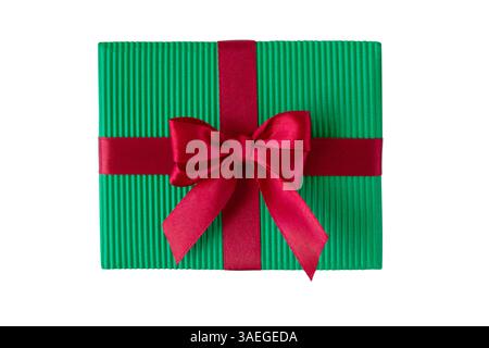 Christmas colors gift box with satin bow top view isolated on white. Box wrapped with green corrugated paper and tied with red shiny silk ribbon. Coqu Stock Photo