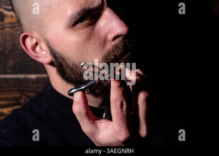 Barbershop advertising. Serious barber. Men hairstyle and haircut. Man with scissors cut beard. Haircare, barber concept. Bearded man with scissors Stock Photo