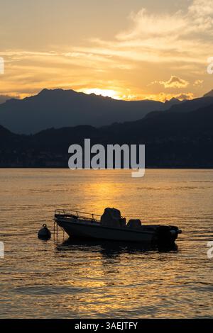 Silhouetted Boat on Golden Lake at Sunset at Varenna, lake Como, Italy Stock Photo