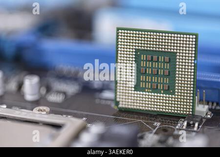 An old computer processor stands on the background of the motherboard Stock Photo