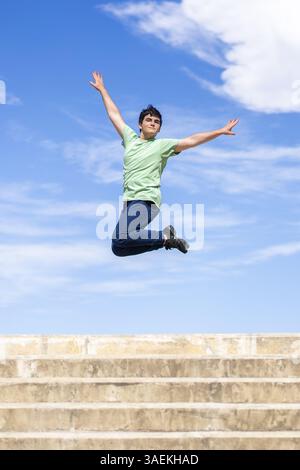 Energetic young man jumping with joy against a clear blue sky Stock Photo