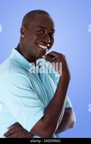 Handsome happy African American corporate business man smiling, wearing blue polo shirt and hand on chin, isolated, New York, USA, North America Stock Photo