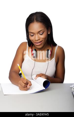 Cute beautiful happy smiling teenage student doing homework writing in notebook sitting at desk, on white, Atlanta, USA, North America Stock Photo