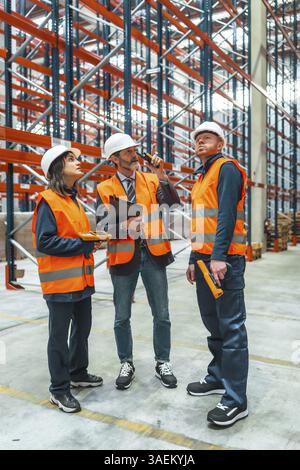 Warehouse workers and their manager are discussing logistics while using a walkie talkie and barcode reader Stock Photo