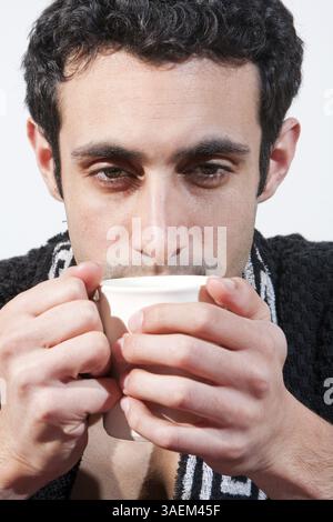 Tired handsome man with a mug wearing a black robe, isolated, New York, USA, North America Stock Photo