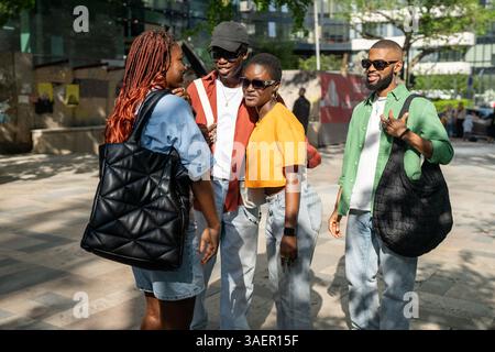 African American multiracial student friends reunite in city, hugging and laughing before day out Stock Photo