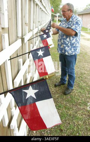 Nov 15, 2004; Angleton, TX, USA; JIMMY JACKSON, of Angleton, Texas, adjusts one flag in a line of Texas flags commemorating Texans killed in Iraq. Jackson has put over 1100 crosses on a wooden fence on his property for all those killed in Iraq. On Monday, November 15th, he was about 25 crosses behind the total of 1188 casualties reported..  (Credit Image: Michael Boddy/ZUMAPRESS.com) Stock Photo
