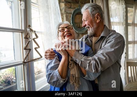 Joyful active old retired romantic senior couple dancing laughing and having fun in living room Stock Photo