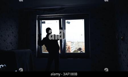 Silhouettes of builders install plastic windows in the house. Stock Photo