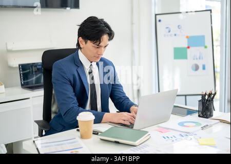 Businessman or male office worker is staring intently at the screen while typing on his laptop. thinking or writing carefully in the office. Stock Photo