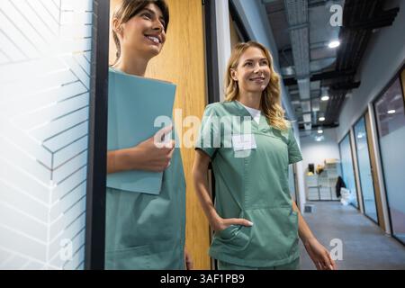 Two female doctors talking in hospital corridor discussing patient's treatment Stock Photo