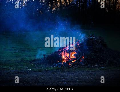 Burning heap from tree cuttings in the night with ember, smoke and sparks, bonfire or traditional Easter fire, copy space, selected focus Stock Photo