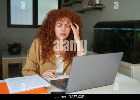 Tired businesswoman suffering from headache working from home office Stock Photo