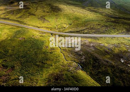 Aerial view of winding road through green hills Stock Photo