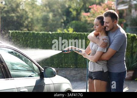 Couple in love wasing car together in the garden at home Stock Photo