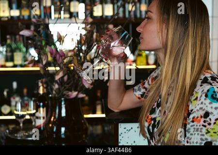 Woman drinking white wine from a glass at the bar counter Stock Photo
