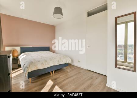 A stylish modern bedroom showcasing a comfortable bed, minimal decor, and a sleek design, featuring a wooden floor and soft color palette. Stock Photo