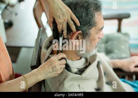 Senior Man getting haircut from Senior wife at home Stock Photo