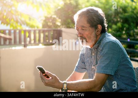 Senior Man using phone outdoors at home Stock Photo