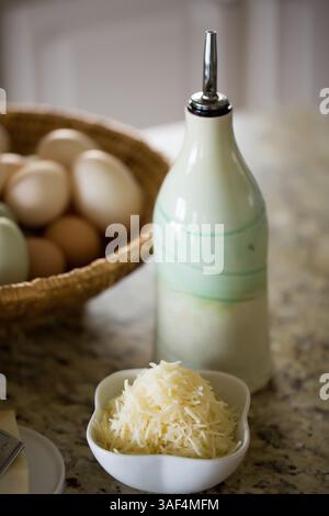 Shredded cheese, eggs, and olive oil bottle on kitchen counter Stock Photo