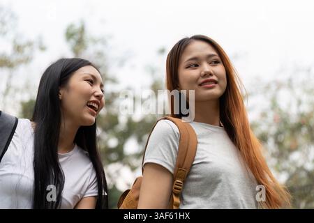 Friendship and School Life. Two students enjoying their time together, sharing laughter and conversation outside their school. Stock Photo