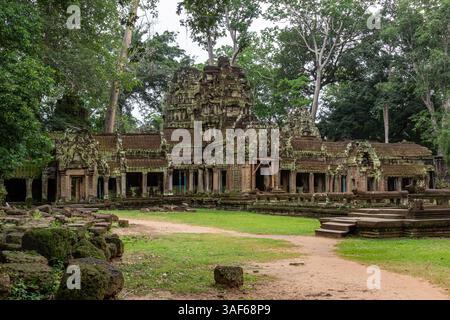 Moss-covered green stone building structure exterior and bricks at Ta Prohm Tomb Raider temple complex in the lush green forest. Angkor Wat historical Stock Photo
