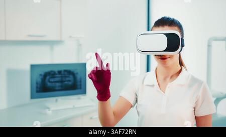 Woman in a medical office using virtual reality headset. A woman wearing a white shirt and red gloves interacts with virtual reality technology in a Stock Photo