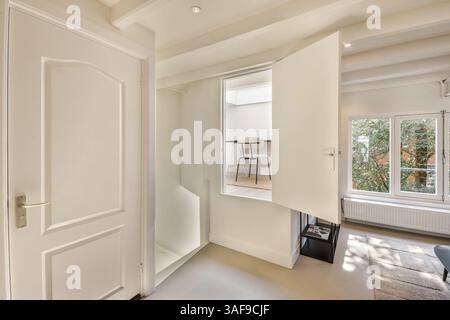 A sleek, well-lit interior showcases a window with an outdoor view, complemented by clean lines and minimalistic furniture that radiates a cozy ambiance. Stock Photo