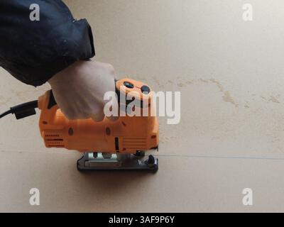 jigsaw on a piece of cardboard or plywood, using a jigsaw in a workshop when working with thin dense hard wood materials, carpenter's tools for cut Stock Photo