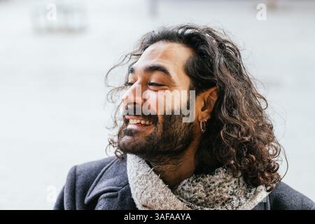 Portrait of smiling man with long hair and earring enjoying winter day Stock Photo
