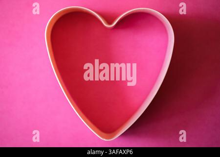 London UK, April 7 2025, Heart Shaped Pastry Cutter Against A Pink Background Stock Photo