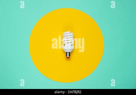 Spiral eco light bulb on a colored paper background. Top view. Minimalistic still life Stock Photo