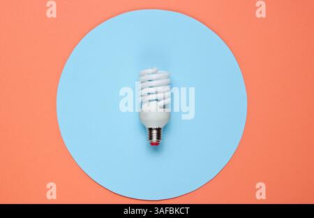 Spiral eco light bulb on a colored paper background. Top view. Minimalistic still life Stock Photo