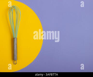 Whisk on blue background with yellow circle. Minimalistic food concept. Stock Photo