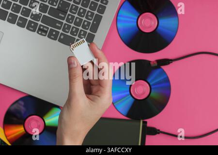 Female hand holds SD memory card on a background of gadgets. Top view Stock Photo