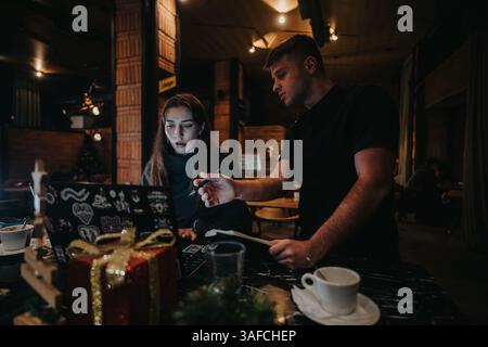 Two coworkers collaborating on a project during holiday season at a cafe Stock Photo