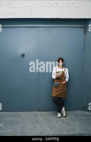 Female Worker Using Phone In Workshop Stock Photo