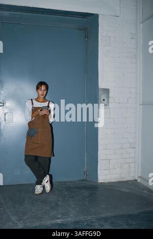Female Worker Using Phone In Factory Stock Photo