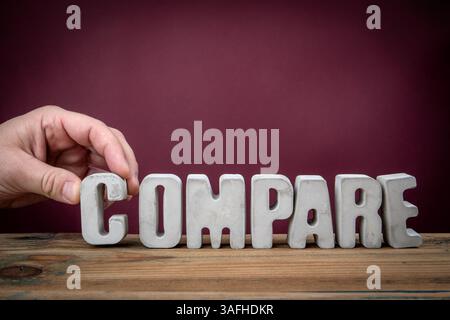 COMPARE Word Created from Concrete Alphabet Letters on Wooden Desk. Stock Photo