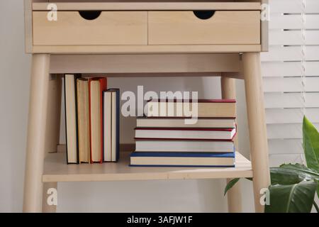 Different books on shelf of nightstand indoors Stock Photo