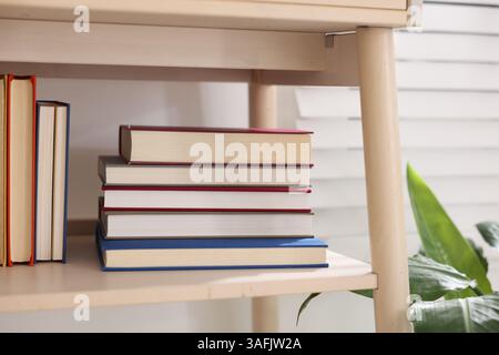 Different books on shelf of nightstand indoors Stock Photo