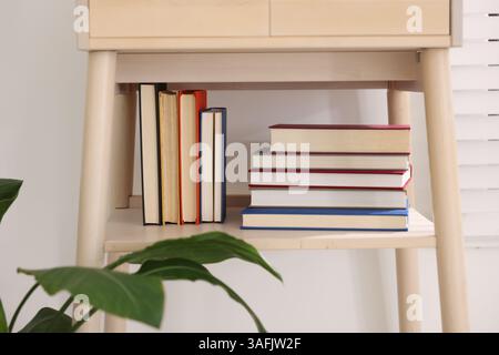 Different books on shelf of nightstand indoors Stock Photo