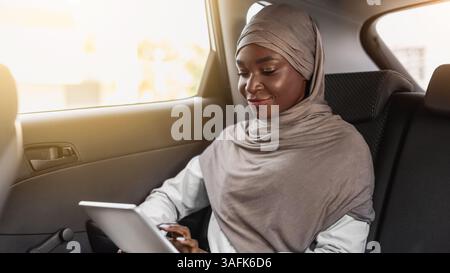 African islamic businesswoman using digital tablet while having trip by car Stock Photo