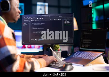 African american computer scientist in home office programming code on pc. Freelancing developer solving tasks for an IT job, writing lines of code at his personal office, cybersecurity. Stock Photo