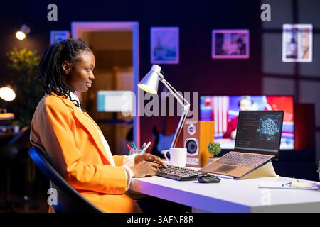 Freelancing computer engineer doing maintenance on artificial intelligence systems. Remote tech support specialist working from home, doing checkup on AI systems using laptop Stock Photo
