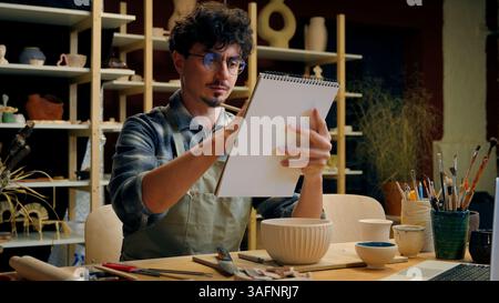 Caucasian man guy artist painting notebook sketch paper drawing male painter designer sculptor potter artwork ceramics paint hobby in studio creative Stock Photo